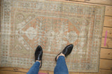Vintage distressed Oushak rug with soft peach, ivory, and seafoam geometric patterns underfoot.
