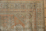 Distressed Oushak rug corner with rhythmic geometric border in sandalwood, peach, and seafoam.
