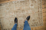 Distressed vintage Oushak rug with faded diamond medallion and soft neutral texture.