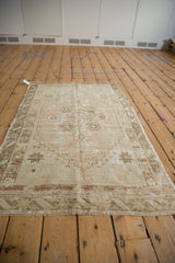 Faded dusty rose and pale coffee brown starburst motifs on a distressed vintage Oushak rug corner.