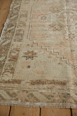 Worn, low pile texture on a vintage distressed Oushak rug with soft dusty rose and ivory tones, showing fringe.