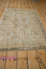 Distressed Oushak rug's bottom edge, showing textural wear, fringe, and coffee brown tones.