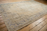 Distressed vintage Oushak corner with worn cream field, faded blue spandrel, and floral motifs.