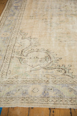 Distressed Oushak carpet detail, highlighting worn texture and faded cream, blue, green motifs.