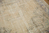 Distressed vintage Oushak carpet pile showing foundation wear and faded blue, green floral motifs.
