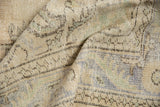 Close-up of distressed vintage Oushak rug, showing low pile texture and muted cream, blue patterns.
