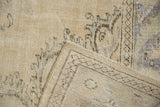 Distressed vintage Oushak rug showing worn pile and woven foundation at corner.