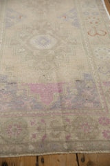 Distressed Oushak rug's worn pile texture showing faint foundation and dusty mauve abrashes.