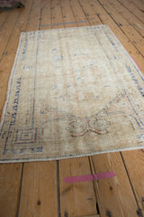 Distressed Vintage Oushak rug end, with worn pile, visible foundation, and faint blue scrolling motif.