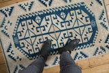 Distressed vintage Oushak rug corner showing dusty navy geometric patterns with worn texture.