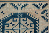 Distressed vintage Oushak rug detail with serrated geometric patterns in dusty navy blue and beige.