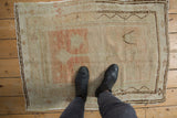 Feet on vintage distressed Oushak rug, showing pale terracotta blossoms, vinery, and worn pile.