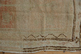 Distressed texture of vintage Oushak rug, showing chocolate brown zig-zag border on pale ivory and blush.