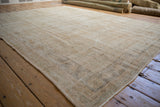 Angled view of the vintage Oushak's textured wear, highlighting diagonal striations and low pile.