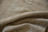 Diagonal striations and textural wear across the knot heads of a folded Oushak carpet.