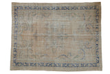 Distressed vintage Oushak rug with muted floral medallion, scrolling tendrils, and cobalt blue border.