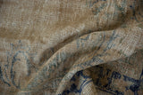 Distressed Oushak carpet texture with softened cobalt blue and seafoam green floral motifs.