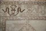 Distressed main border of vintage Oushak rug, brown cloudband motifs, visible knot wear.