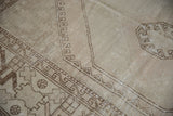 Distressed vintage Oushak rug showing geometric chocolate brown borders and even wear on ivory.