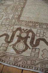 Distressed vintage Oushak rug detail: ivory and brown geometric hook-and-latch, serpent border.