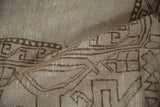 Close-up of distressed Oushak carpet texture, chocolate brown geometric pattern, visible knot heads.