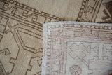 Distressed Oushak rug's antique ivory and brown pile, revealing pale mauve reverse and intact selvage.