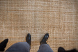 Distressed vintage Oushak rug surface, showing subtle pattern and worn pile in gold and beige.