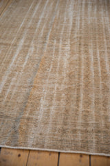 Textured detail of vintage distressed Oushak carpet with linear wear and light tones.
