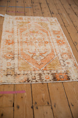 Close-up of distressed vintage Oushak rug showing exposed foundation, ivory, and orange lozenge.