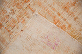 View of distressed Oushak rug's woven foundation with purple mark and short orange pile.
