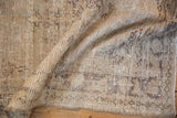 Folded vintage distressed Oushak rug, highlighting worn texture and muted silver charcoal patterns.