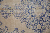 Distressed vintage Oushak carpet, worn navy blue serrated motifs revealing a pale coffee brown pile.