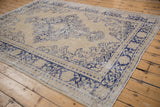 Distressed Turkish Oushak rug corner showing faded navy floral and geometric border.