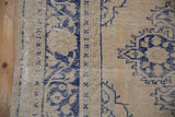Worn hand-knotted pile and distinct cobalt blue floral motifs on a distressed vintage Oushak rug.
