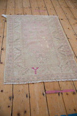 Distressed pink and beige Oushak rug's bottom fringe with vibrant fuchsia mark.
