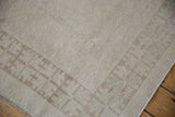 Distressed Oushak rug corner with worn antique ivory pile, faint foundation, geometric border.