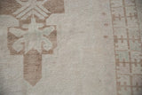 Textured pile of a distressed Oushak rug with primitive pale brown and ivory patterns.