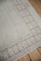 Distressed Oushak runner: worn ivory pile with abstract quatrefoil border pattern.