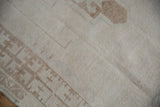 Distressed Oushak rug pile, close-up of antique ivory and pale coffee patterns.