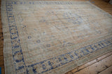 Vintage distressed Oushak carpet with worn texture, visible foundation, faded ivory and blue patterns.