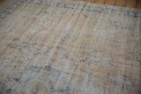 Worn ivory pile and exposed foundation of a distressed Oushak rug with faded blue motifs.