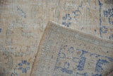 Distressed Oushak rug with worn pile, visible foundation, and faded blue pattern at corner.