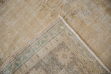 Distressed Oushak carpet with worn pile, green pattern on foundation, intact selvage, and fringe.