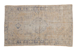 Distressed vintage Oushak rug with faded cream and dusty blue floral medallion.