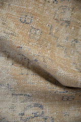 Textured detail of vintage distressed Oushak rug, showing worn cream pile and faded denim blue motifs.