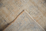 Vintage distressed Oushak rug corner showing worn cream pile, blue patterns, and visible foundation.