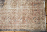 Distressed Sparta rug corner, faded floral motifs, visible foundation, secured edge.