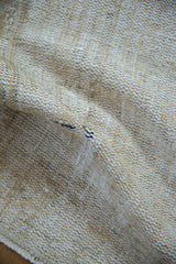 Distressed vintage Oushak rug texture with worn knot heads, beige, cream, and hints of blue.