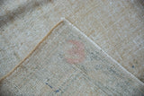 Distressed Oushak rug reverse with painted number; worn pile reveals beige, green, and blue threads.