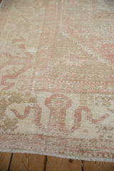 Distressed Oushak rug detail showing dusty rose ram's horn motif and ivory foundation wear.